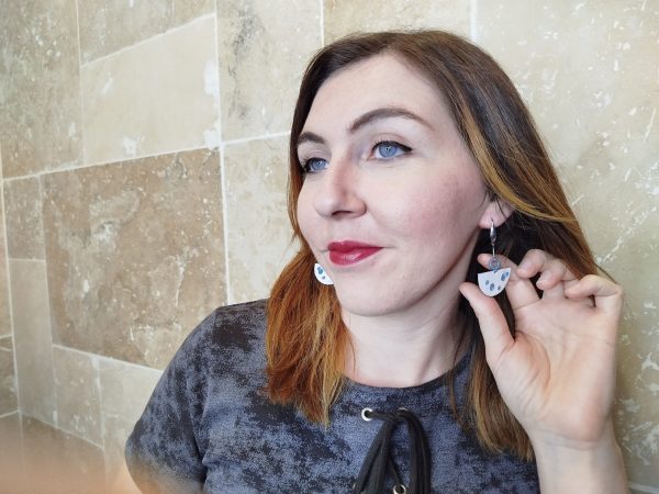 Jeune femme portant les boucles d'oreille de couleur blanches et bleu turquoise en cuivre émaillé
